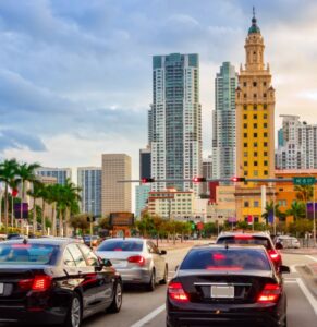 Multiple cars at a stop light in downtown Miami where people are wondering why auto insurance rates are going up.